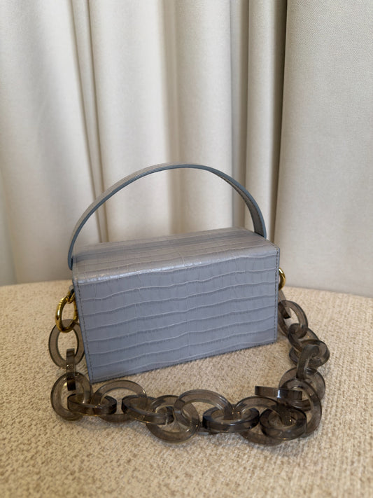 L’AFSHAR Ida light grey embossed leather bag back view with lucite chain