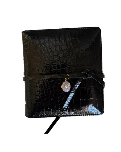 Black croc embossed Elali journal with purple pearl locket charm on a clean white background